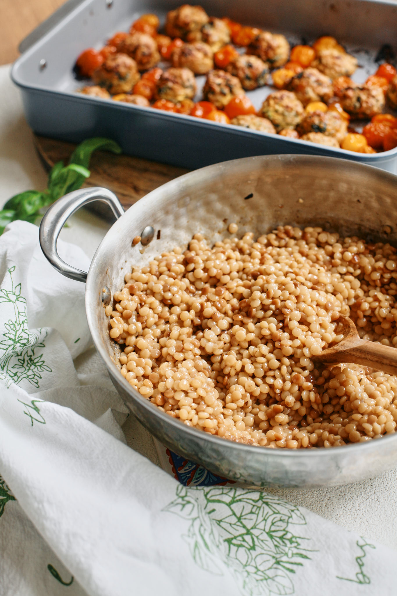 cooked pearl couscous and chicken florentine meatballs with roasted tomatoes ready to plate up