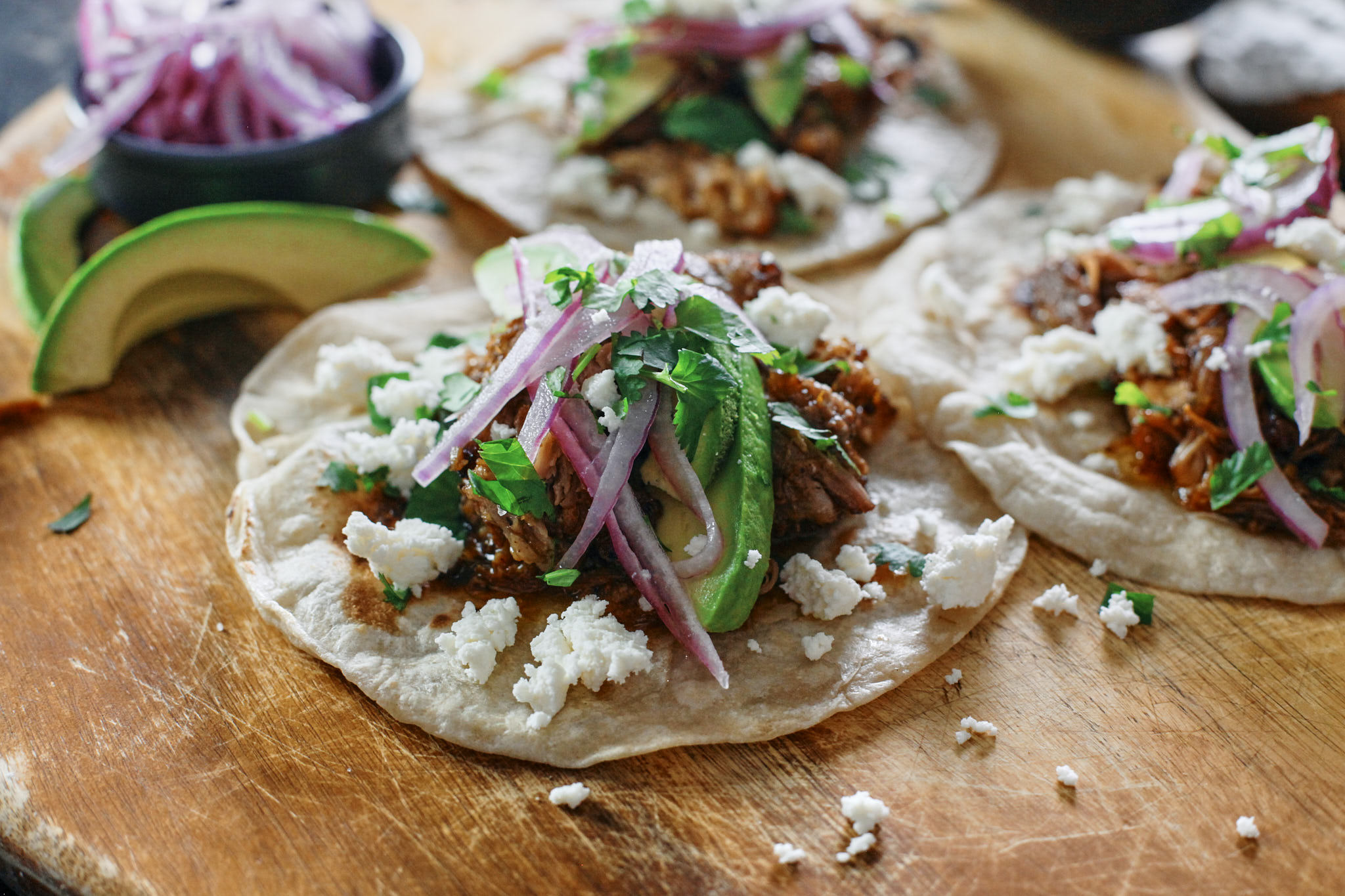 citrus braised pulled pork tacos with avocado, pickled onions, cilantro, queso fresco