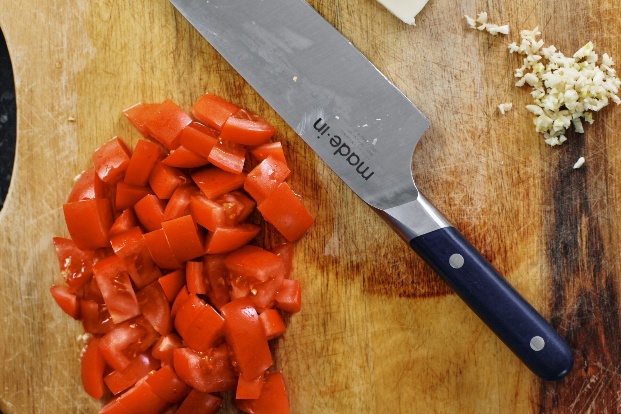 fresh chopped tomatoes on a wooden cutting board with a knife