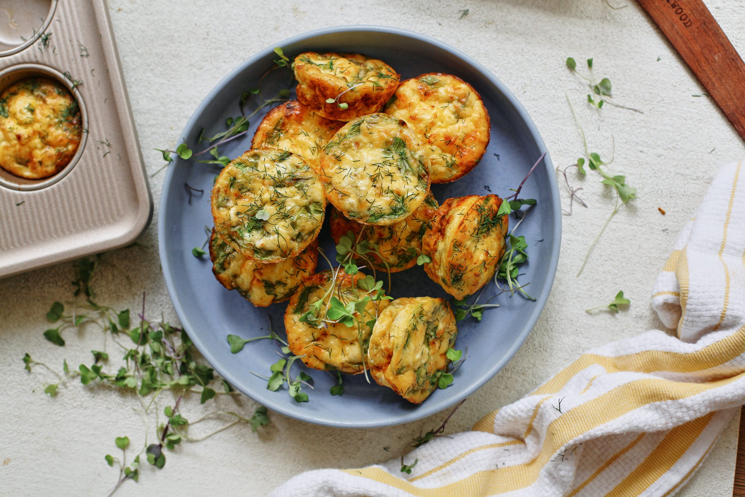 mini spring frittata bites in a blue serving bowl, topped with micro greens