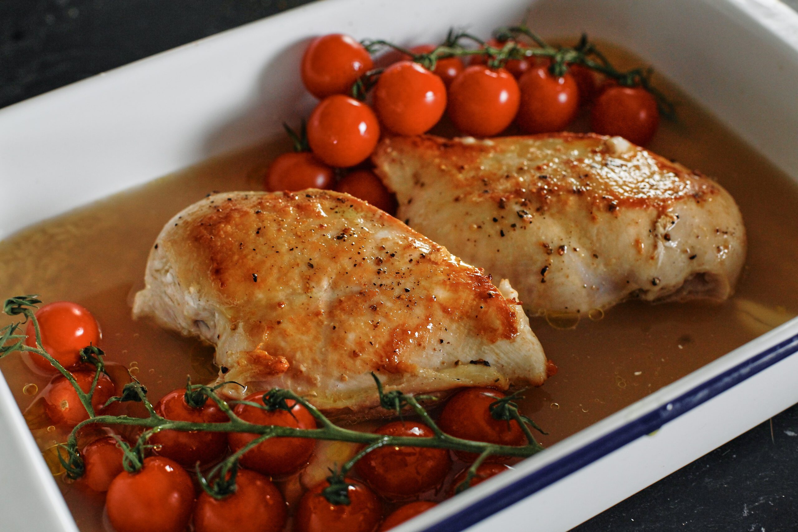Boursin-Stuffed Chicken with Orzo & Tomatoes 6 seared chicken breasts in a baking dish ready to go into the oven with cherry tomatoes, over a mixture of broth and orzo
