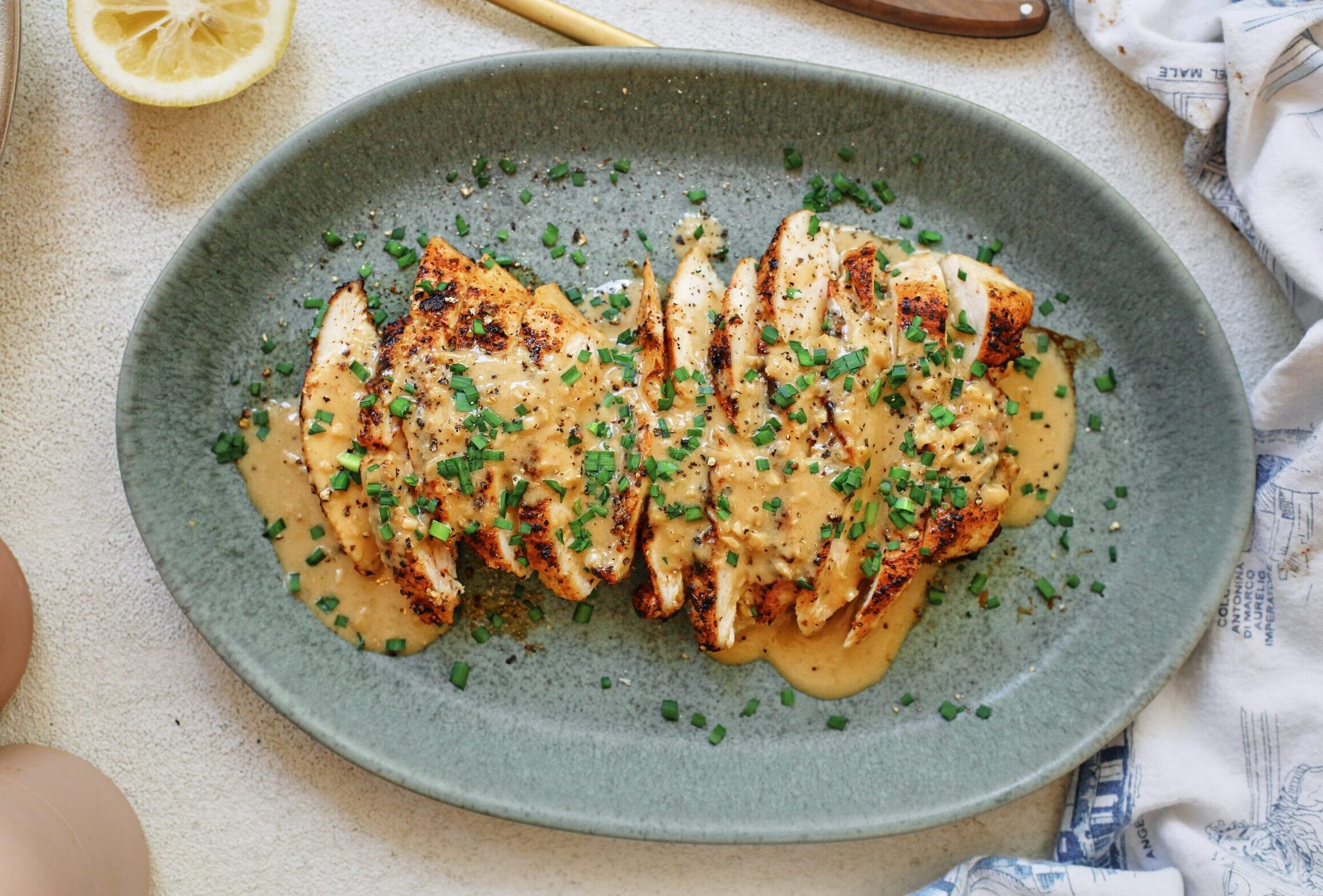 sliced chicken breast with the garlic shallot cream sauce poured on top finished with chives