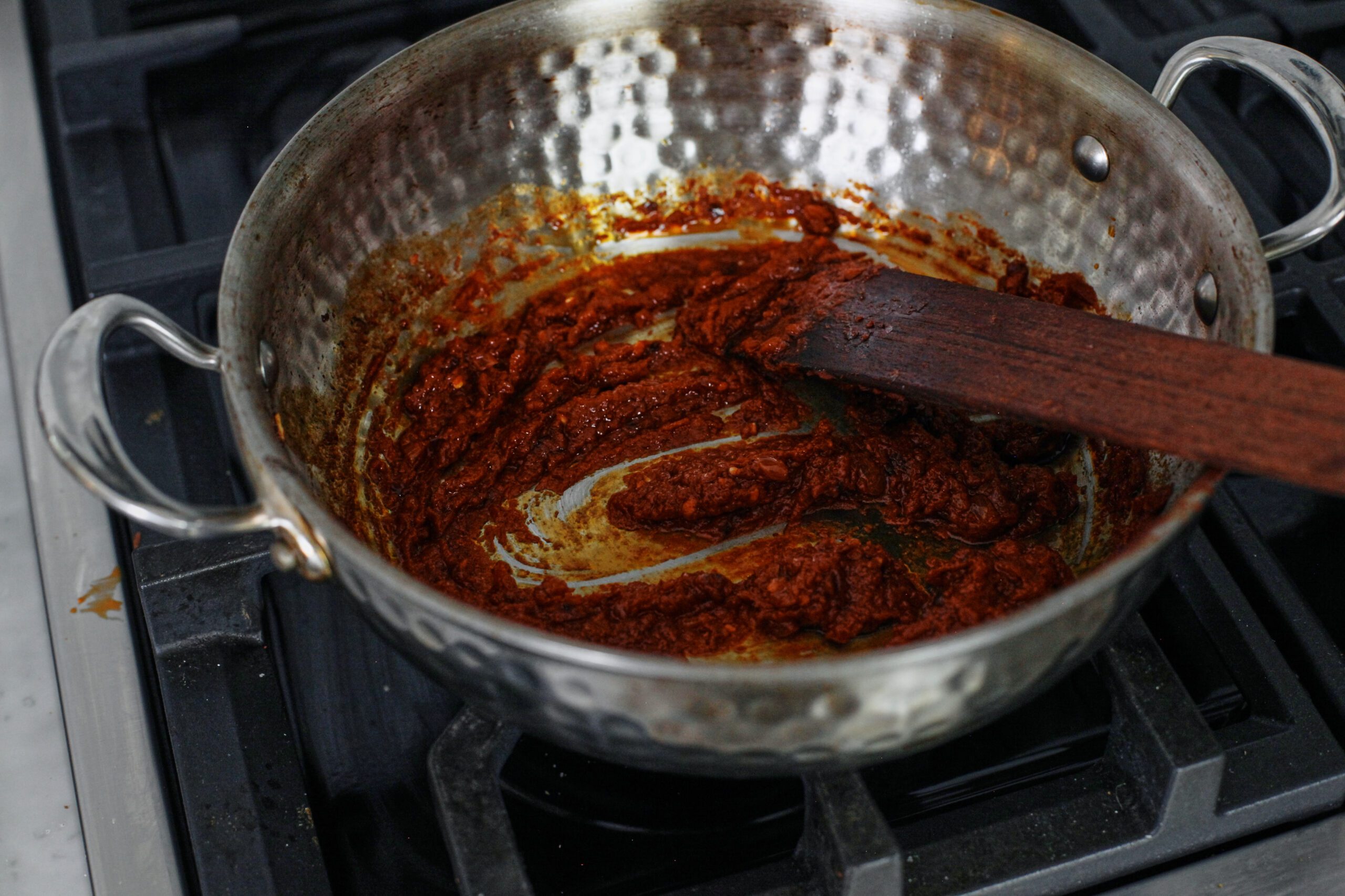 tomato paste and chili oil being cooked in a pan
