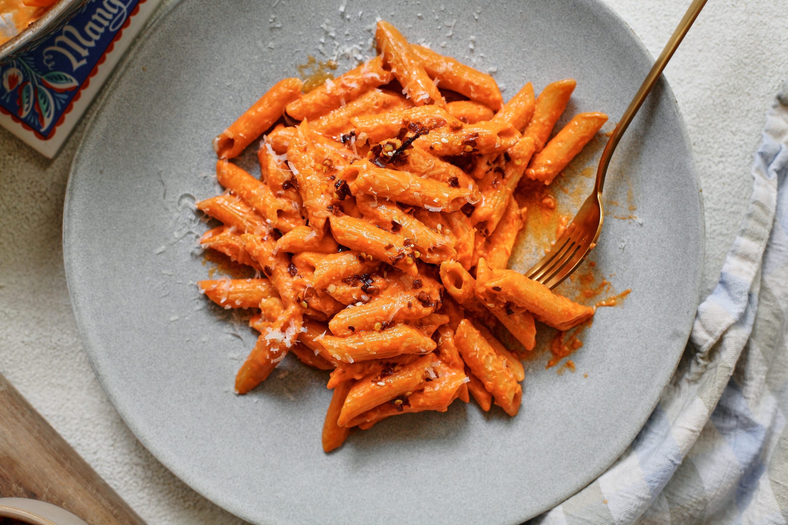 chili oil penne alla vodka on a plate with a gold fork