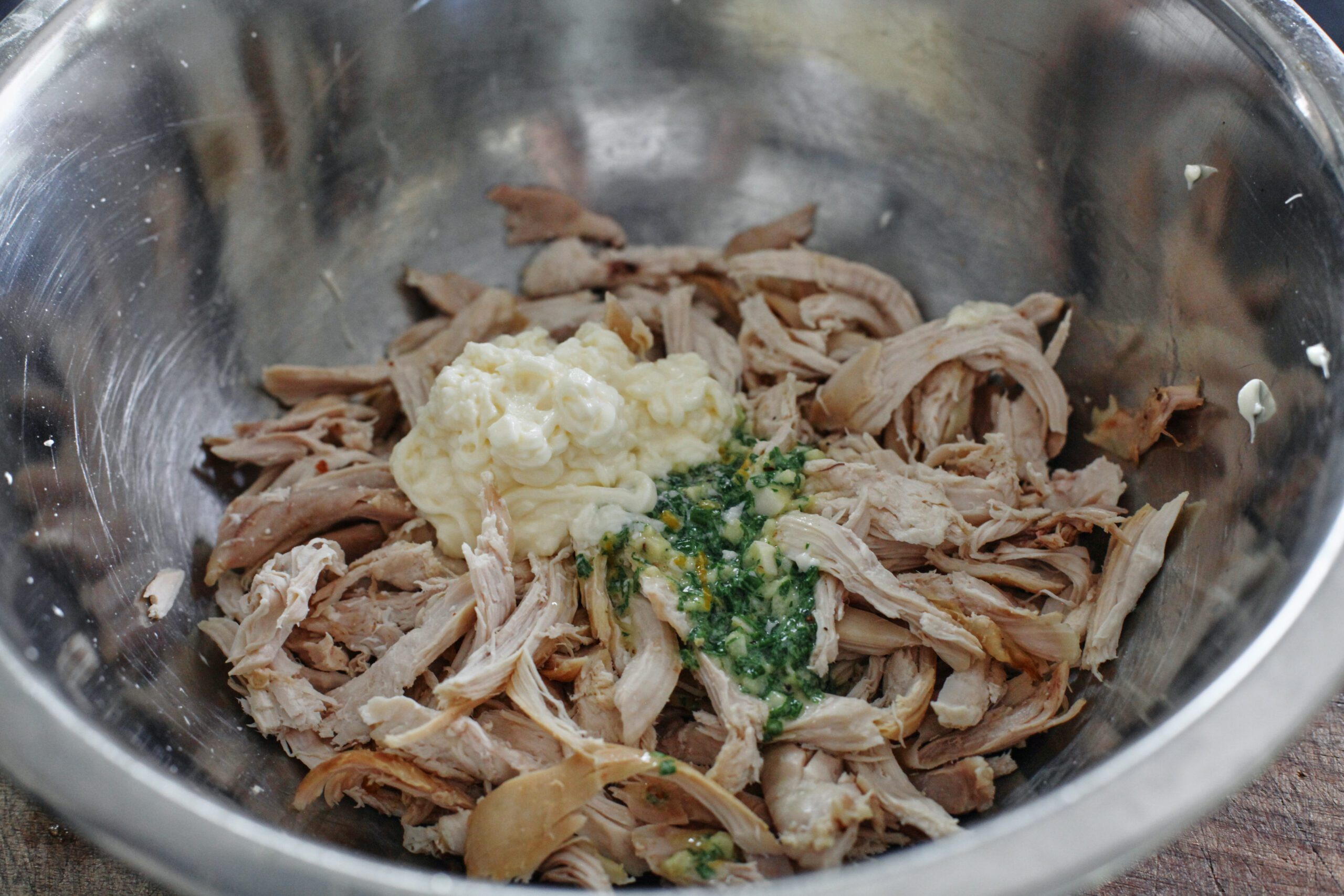 Shredded chicken in a metal bowl with cowboy butter and mayonnaise