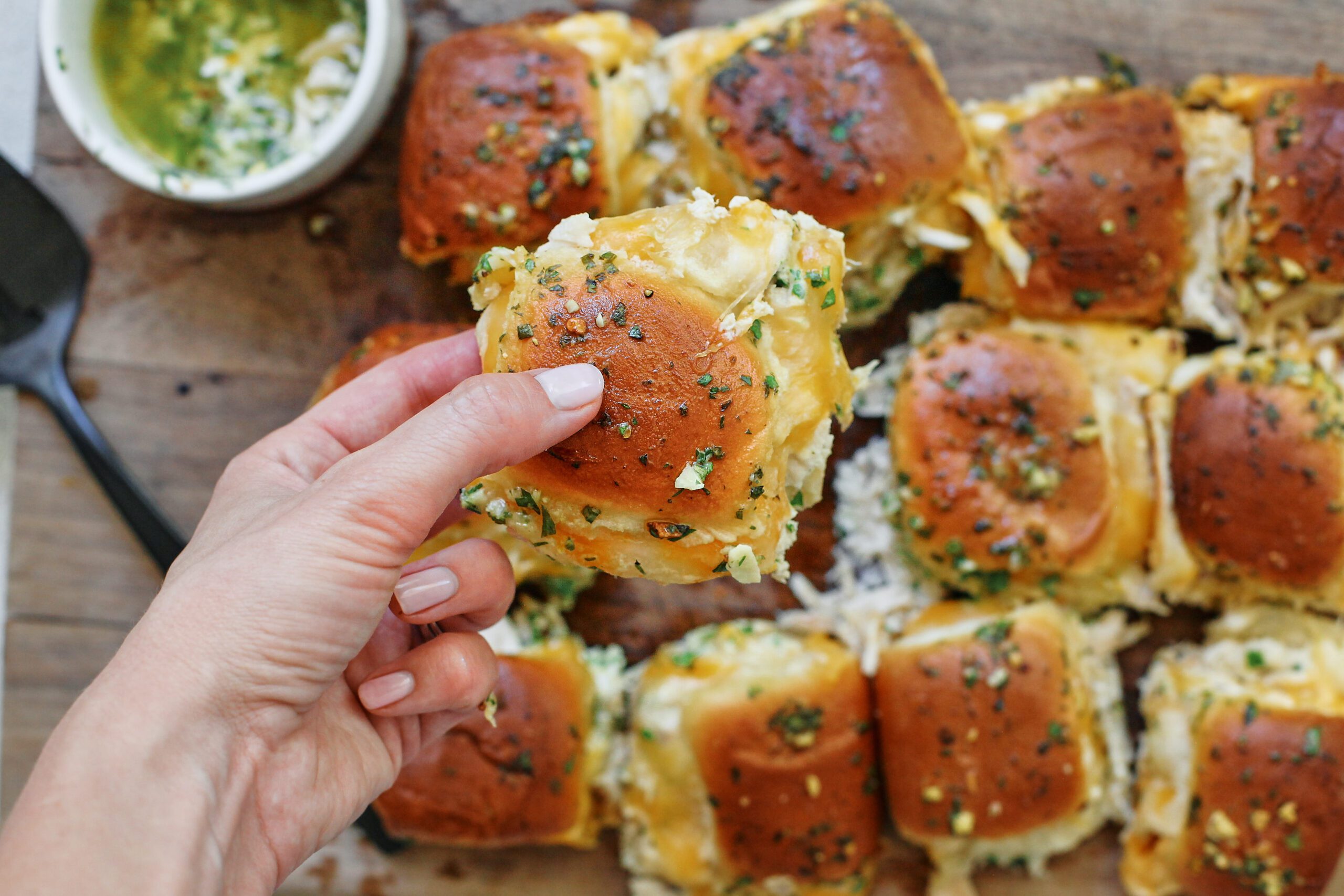 a hand holding one shredded chicken slider