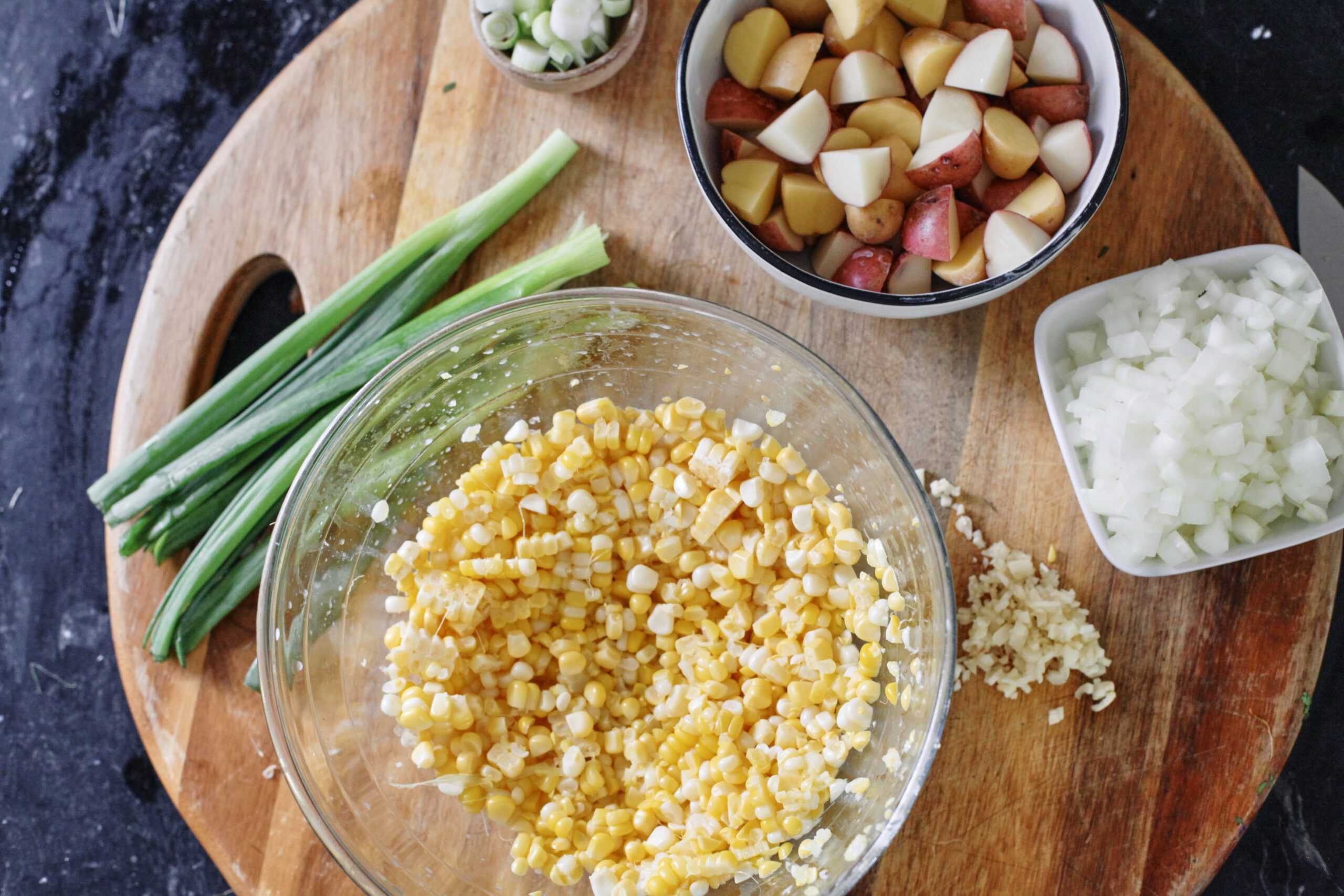 prepped ingredients for creamy corn chowder: green onions, corn, potatoes, garlic, onion