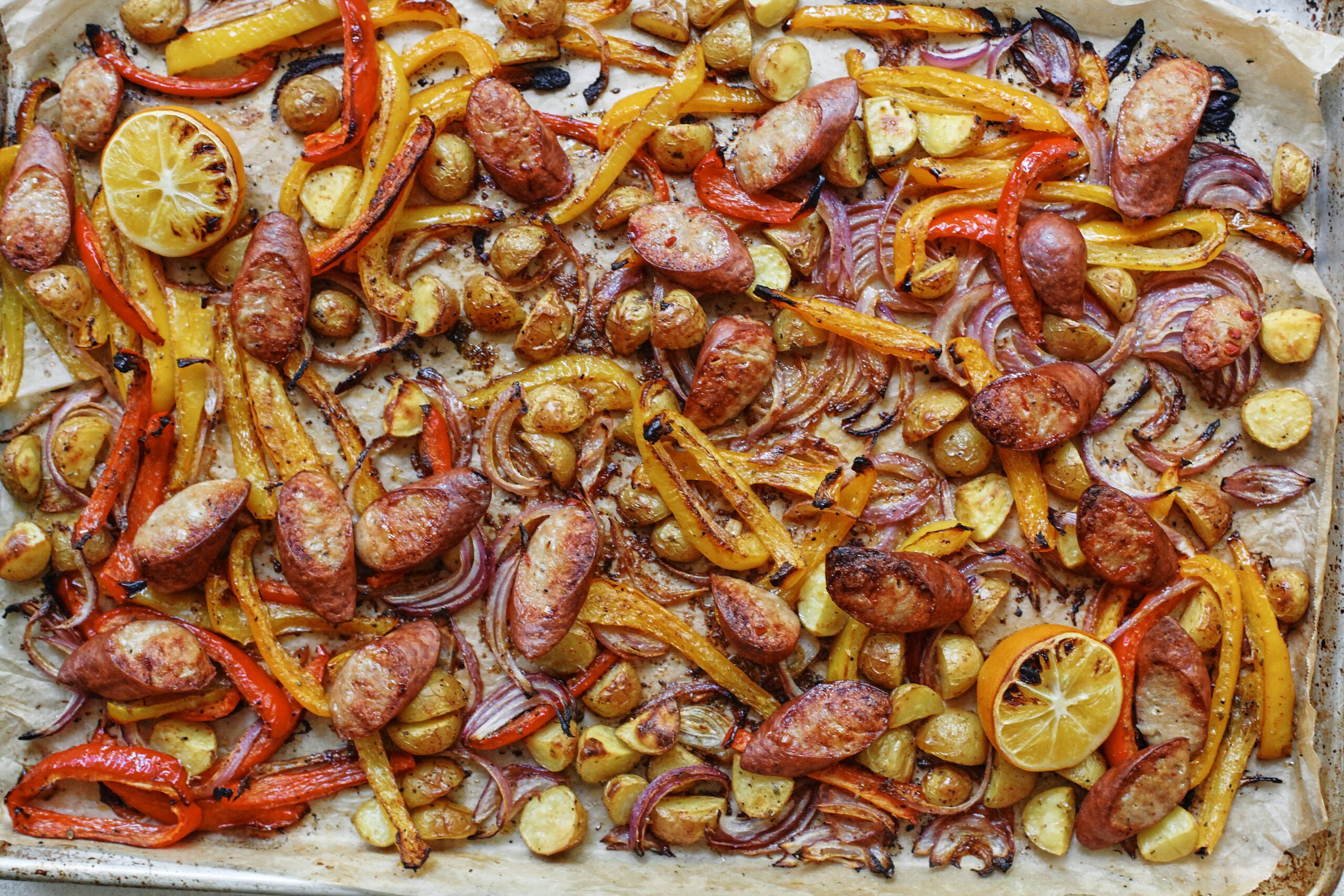sheet pan sausage, peppers, and potatoes on a sheet pan, cooked, after roasting in the oven