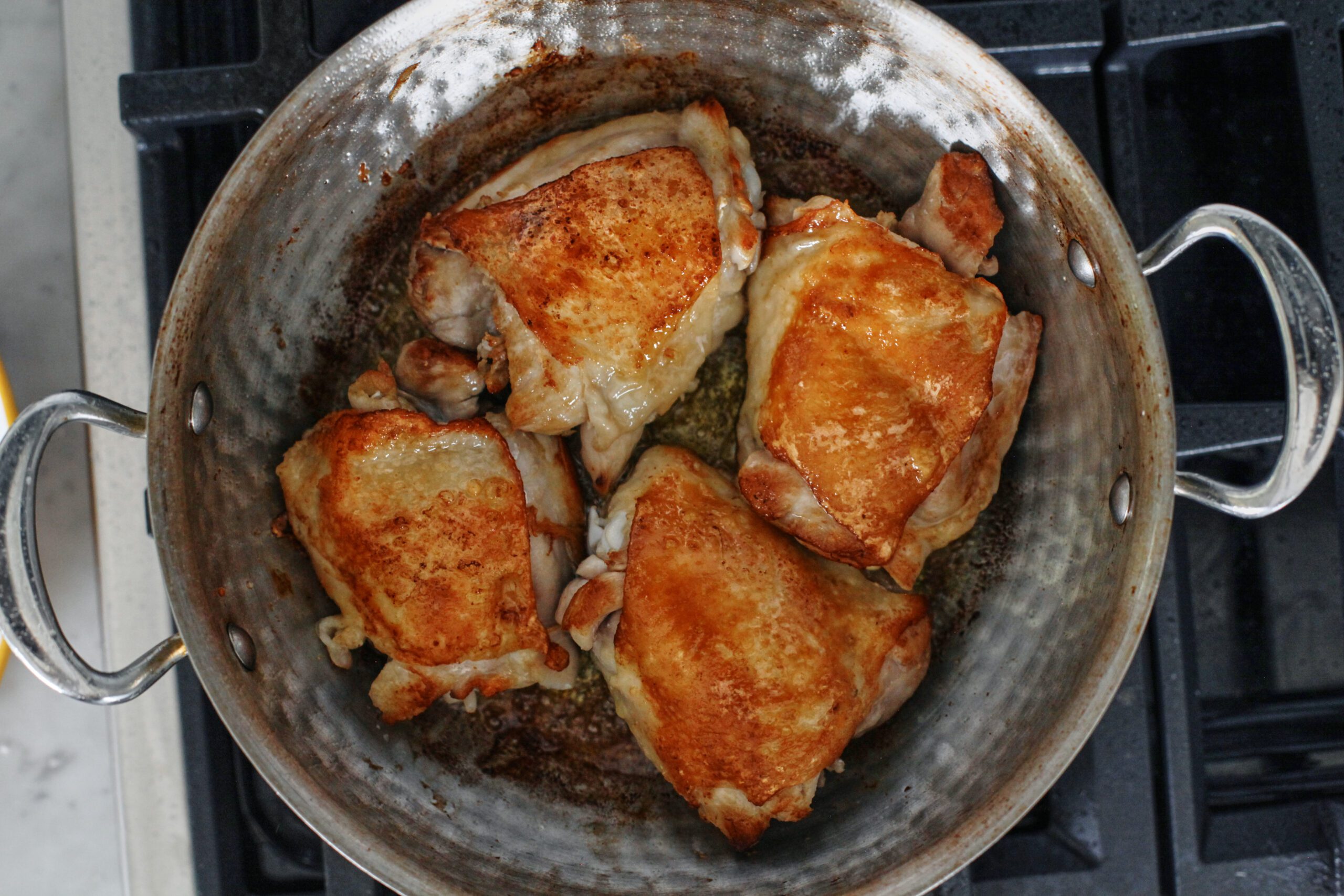 golden chicken thighs searing in the skillet