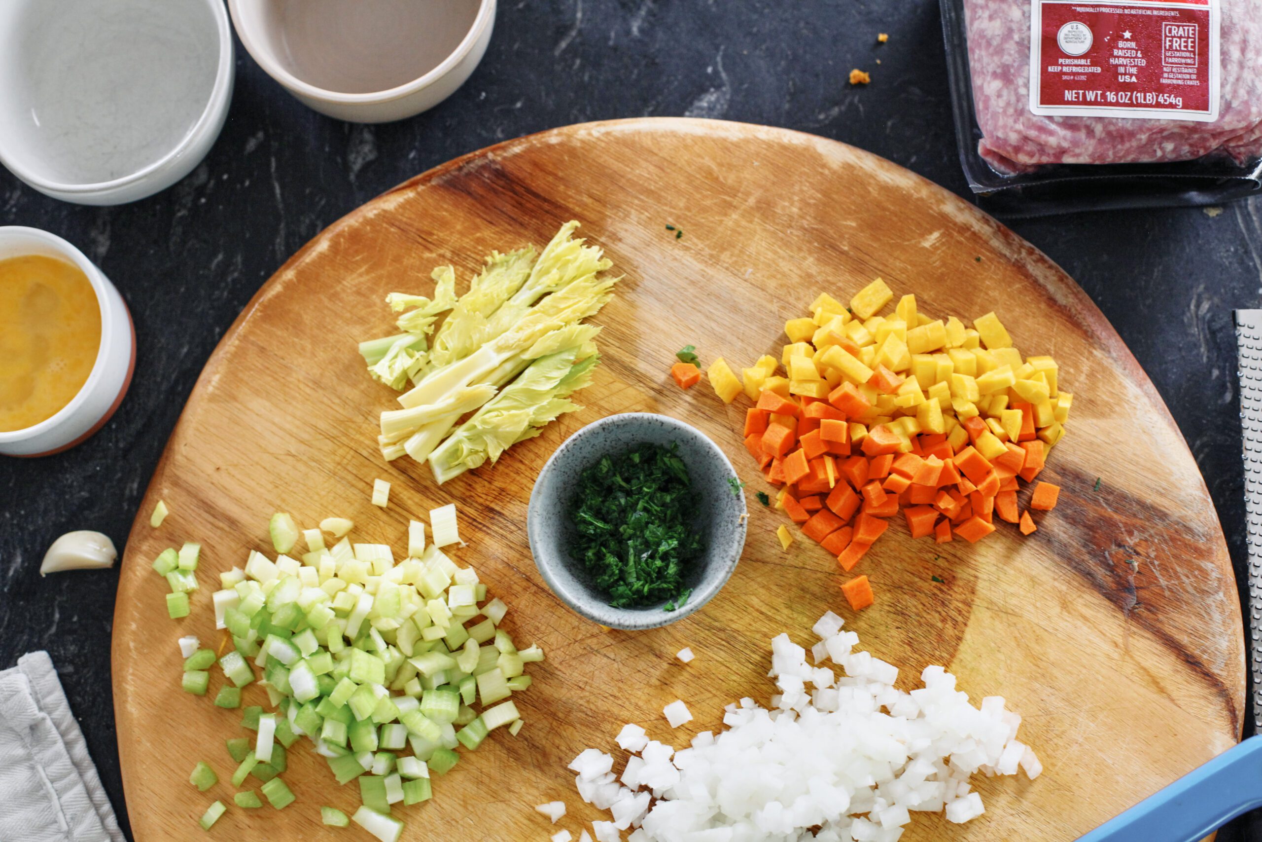 prepped ingredients for italian wedding soup: chopped celery, celery leaves, chopped parsley, chopped yellow + orange carrot, chopped onion
