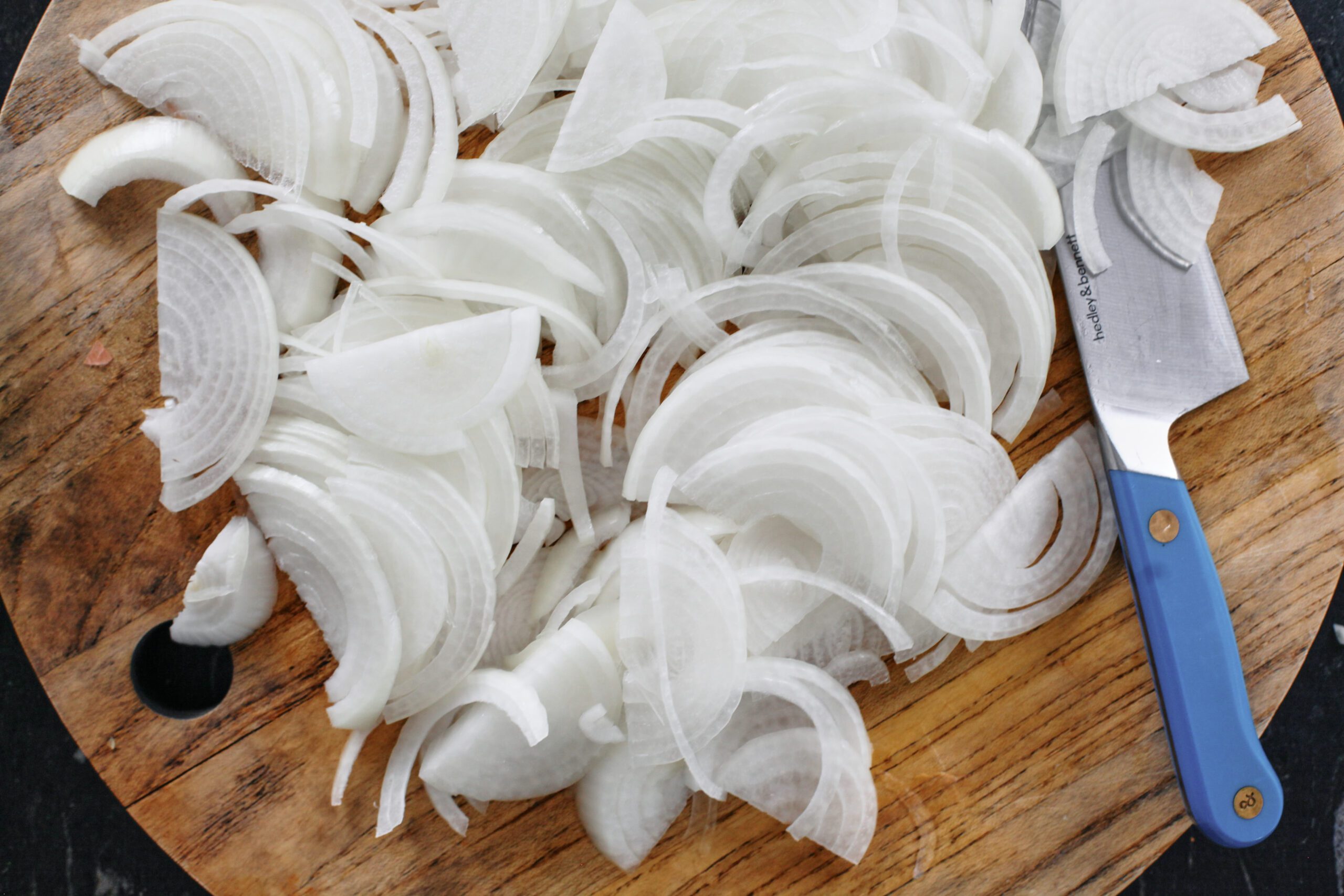 sliced onions on a cutting board with a blue-handled knife