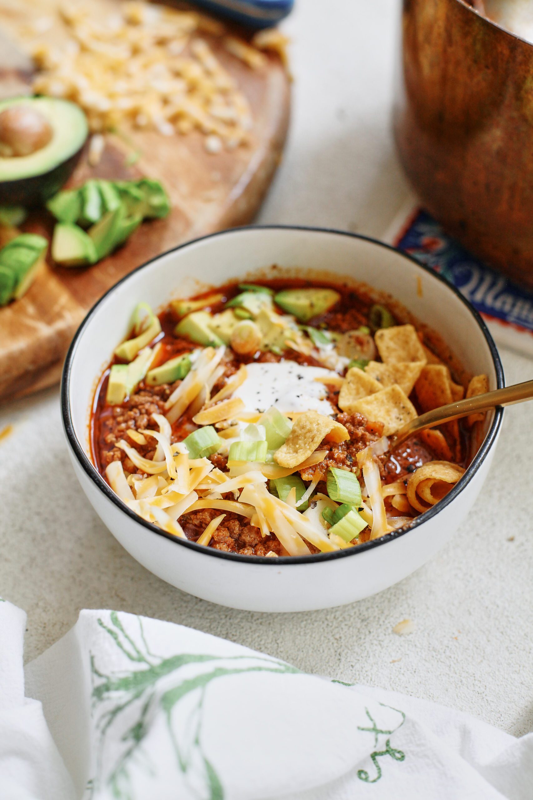 texas style chili topped with sour cream, avocado, green onions, shredded cheese, and fritos