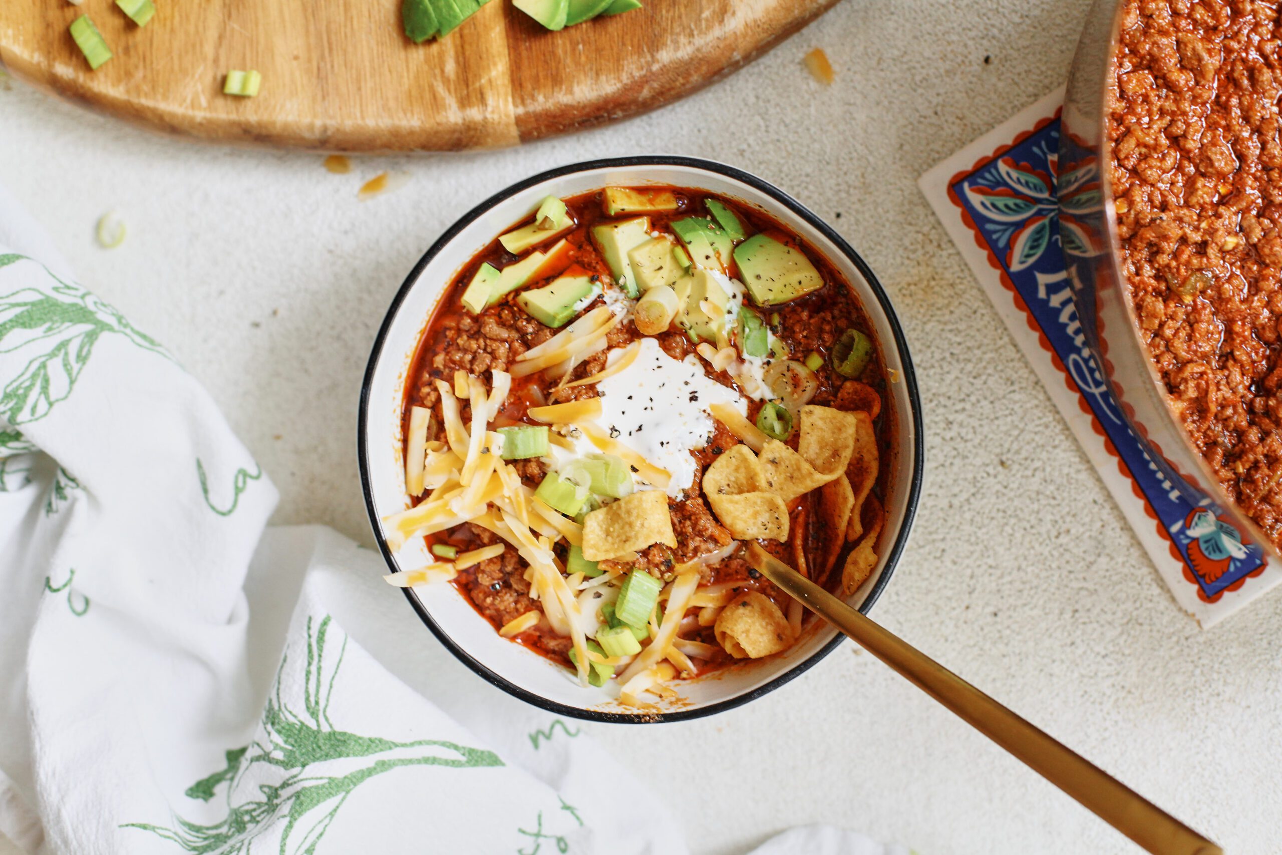 texas style chili topped with sour cream, avocado, green onions, shredded cheese, and fritos