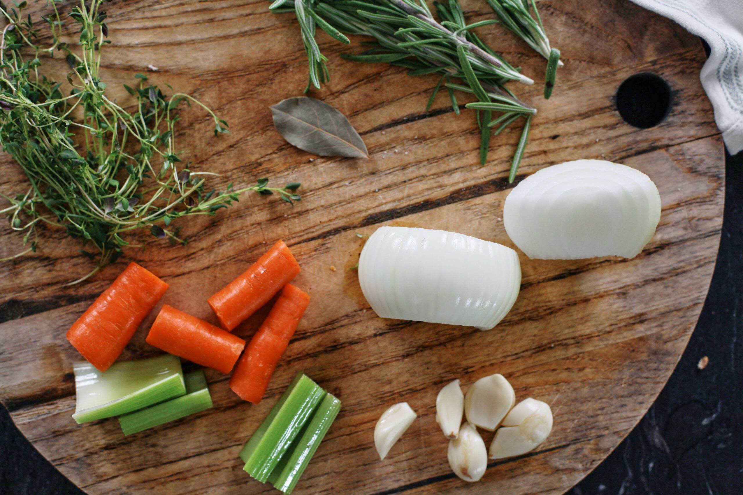 prepped ingredients for the marinade: chopped onion, carrots, celery, cloves of garlic, a bay leaf, sprigs of thyme and rosemary