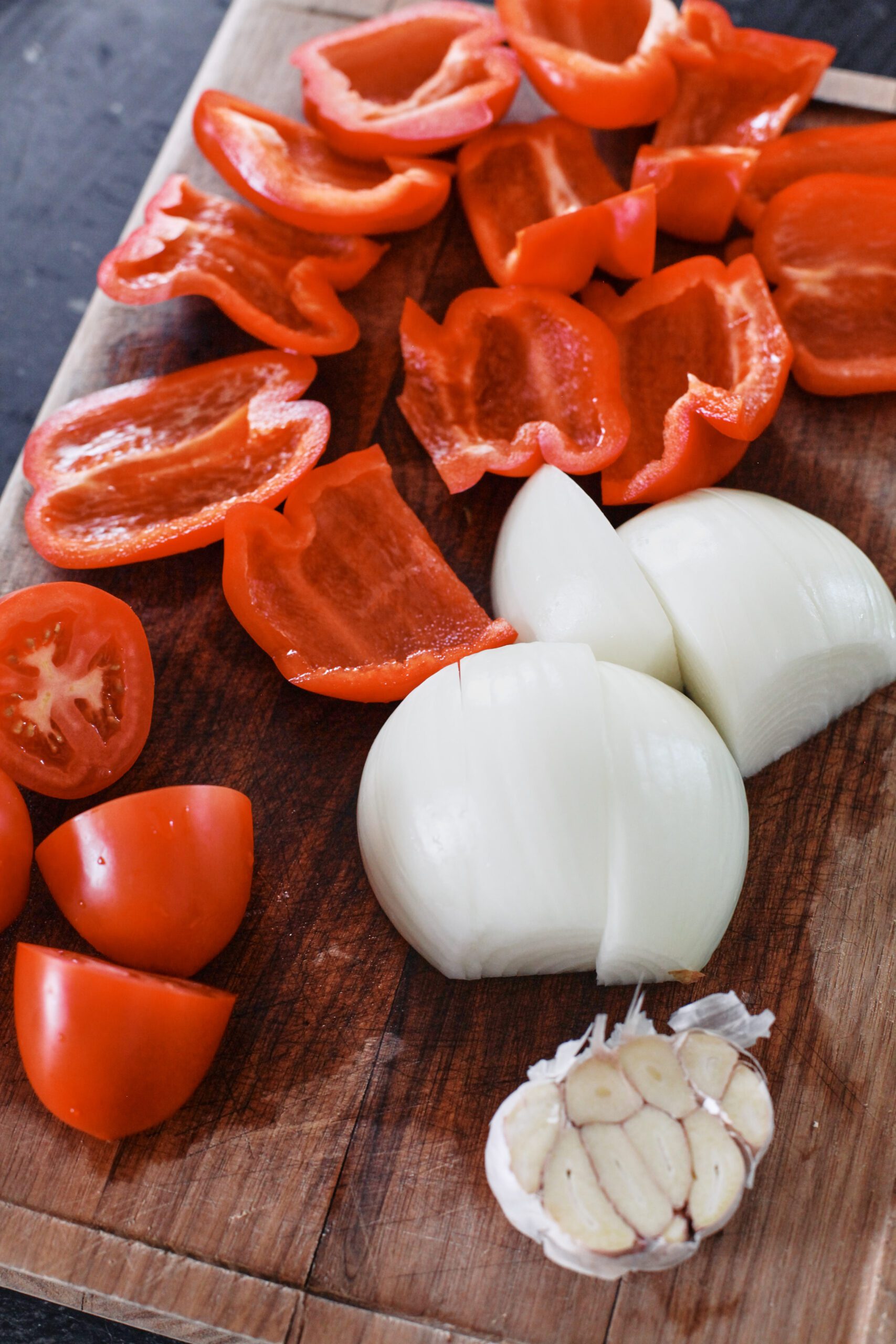 red bell peppers, tomatoes, an onion, and a head of garlic before being roasted