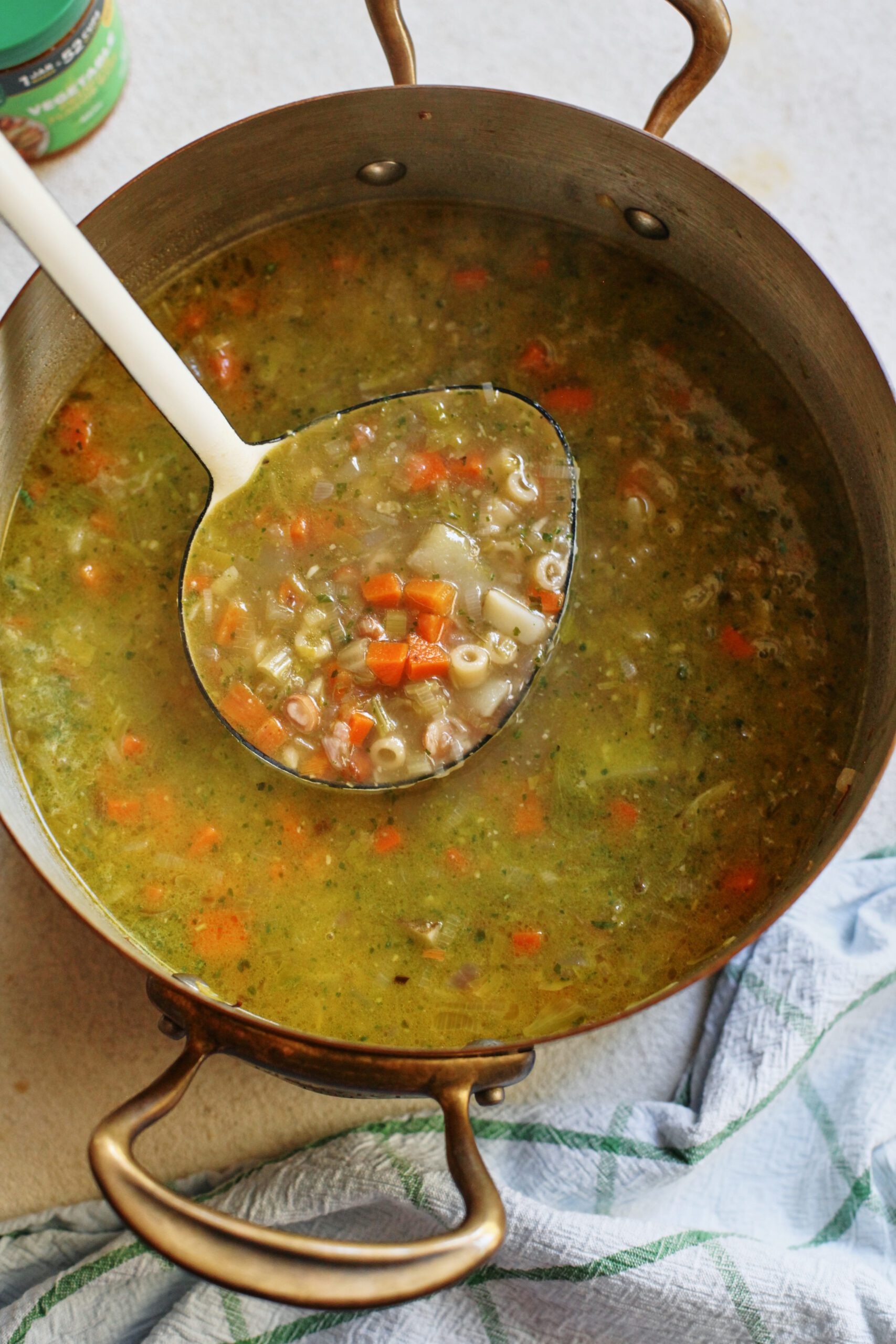 pesto minestrone soup in a large pot with a white ladle