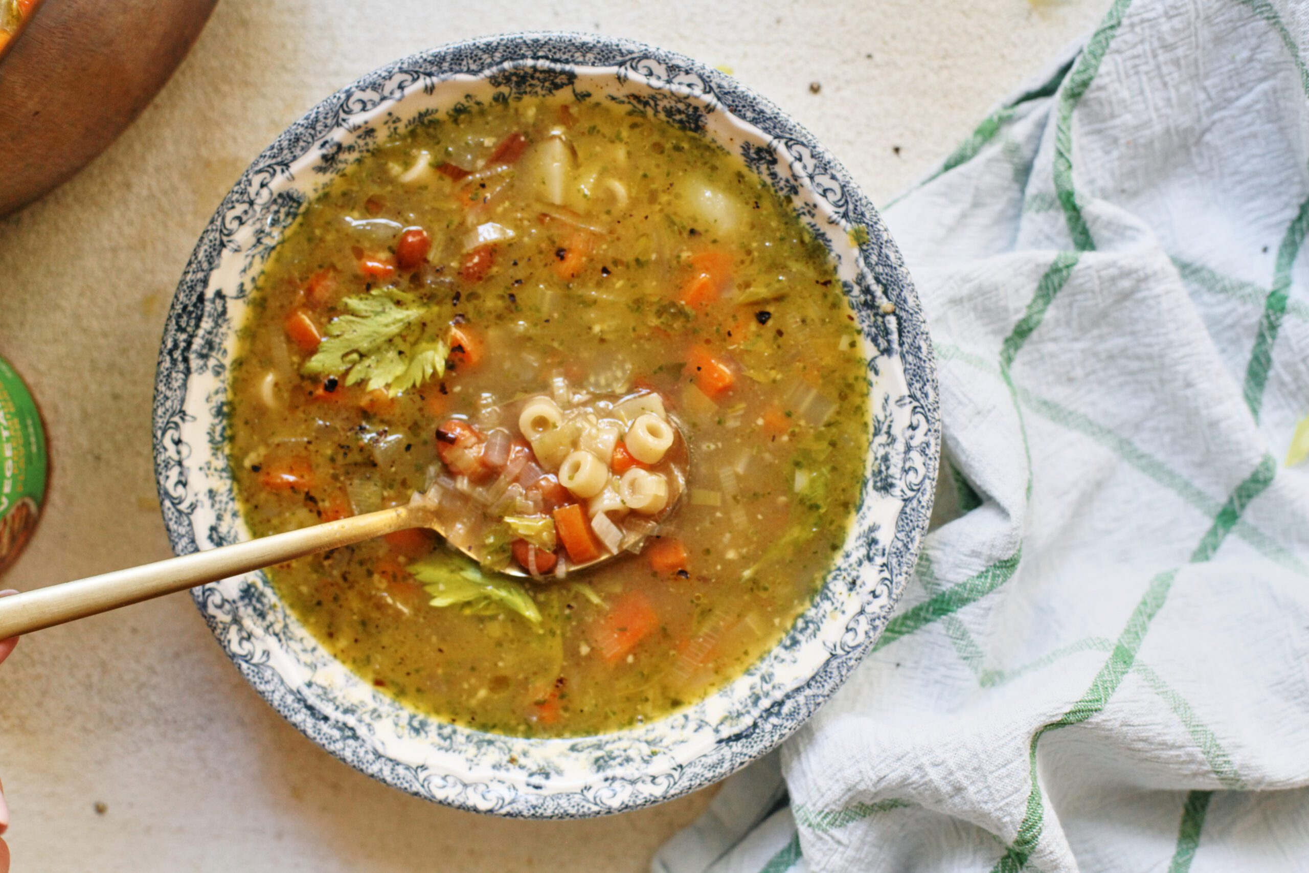 pesto minestrone soup in a white and blue floral-patterned bowl