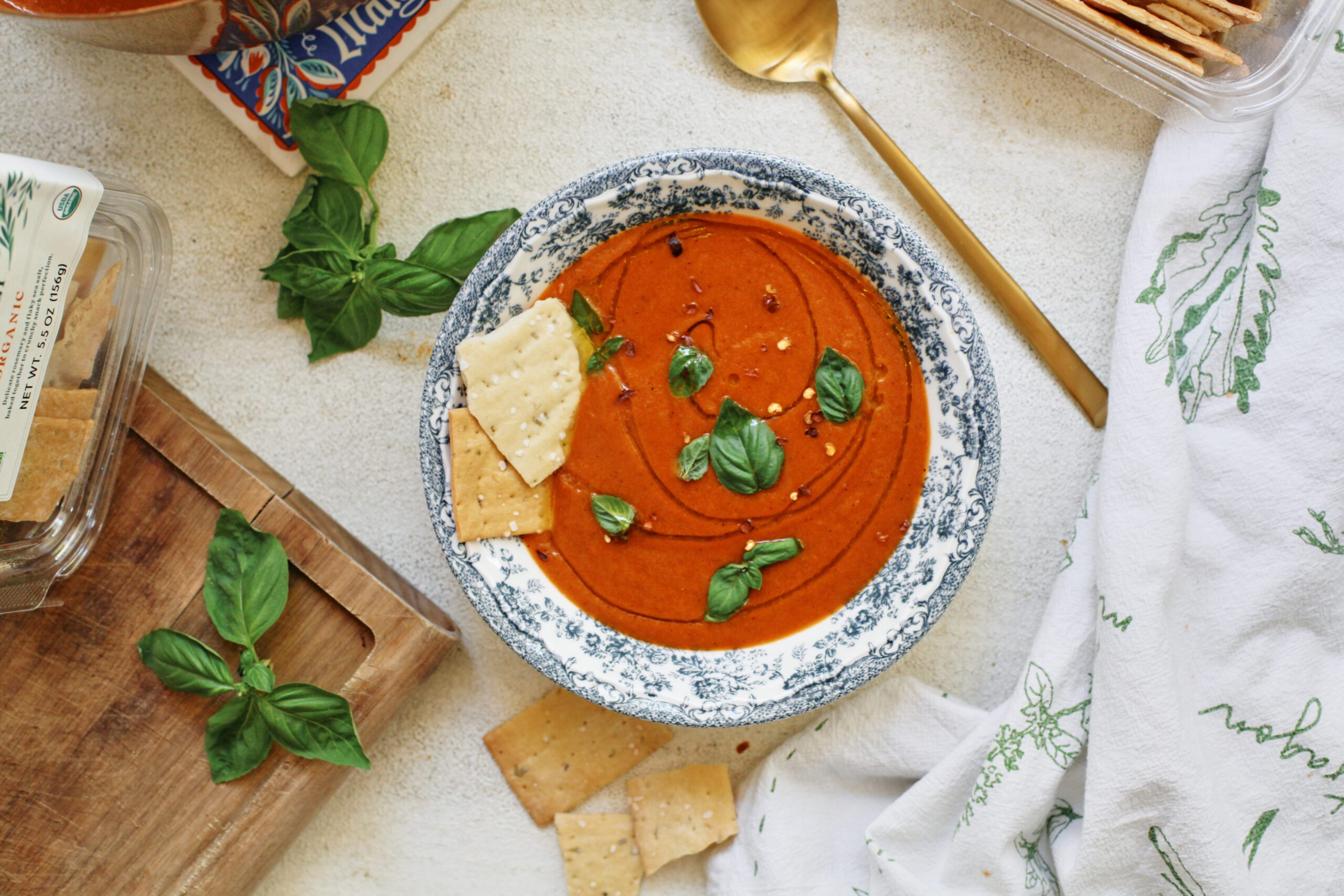 Roasted Red Pepper White Bean Soup 5 Roasted Red Pepper & White Bean Soup in a white bowl with a blue floral pattern, garnished with basil, olive oil, red pepper flakes, and Firehook Rosemary Sea Salt Crackers