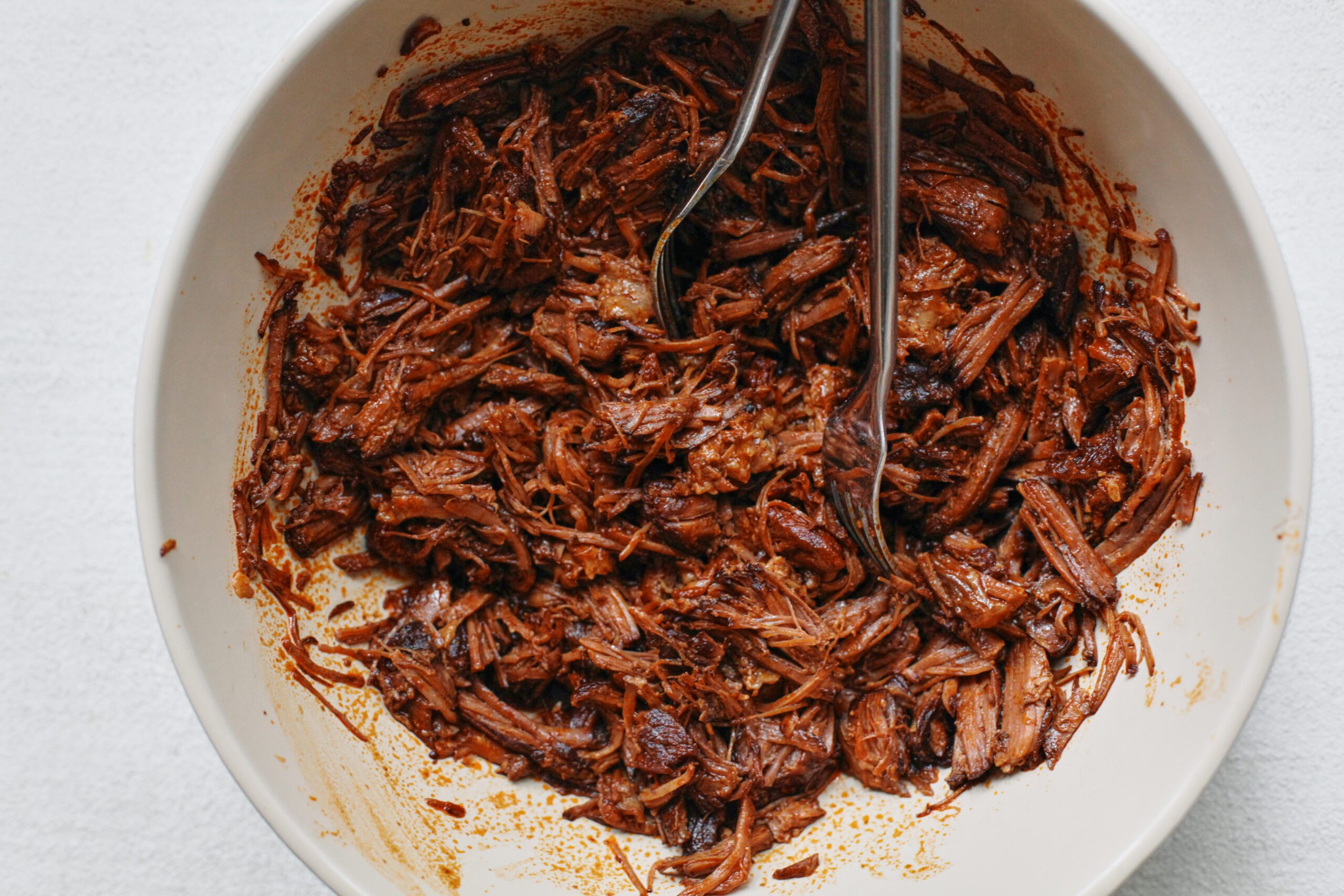chuck roast being shredded with two forks after being pressure cooked