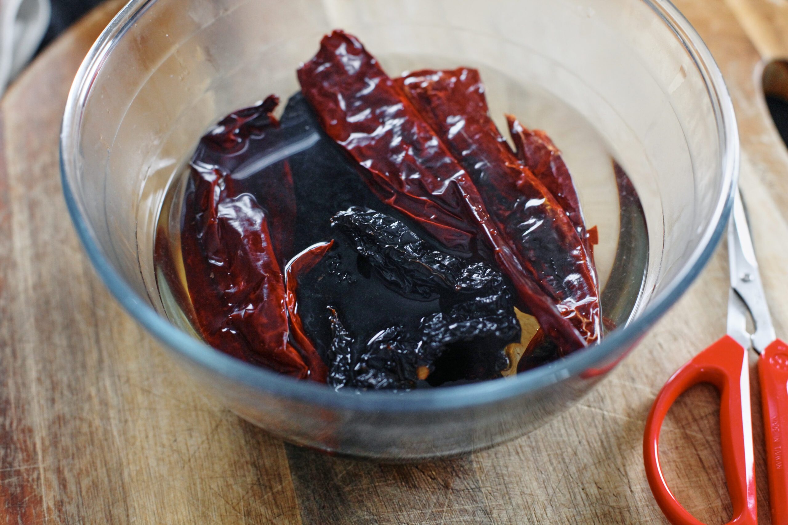 dry chiles steeping in hot water in a glass bowl