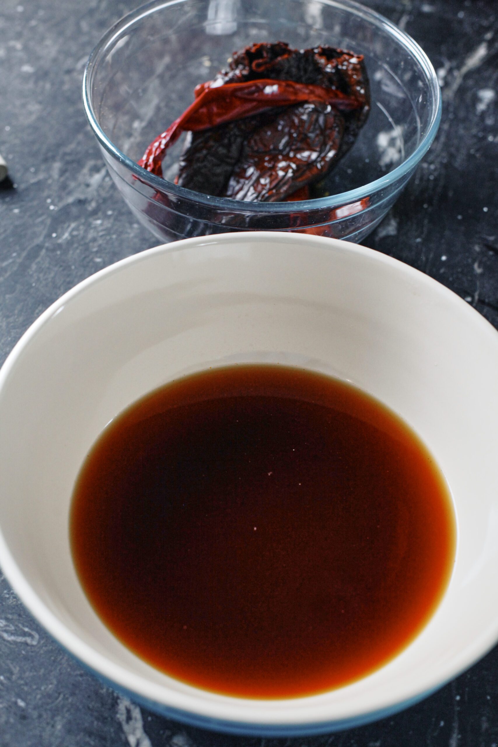 the chile water poured into a white bowl after the chiles were removed