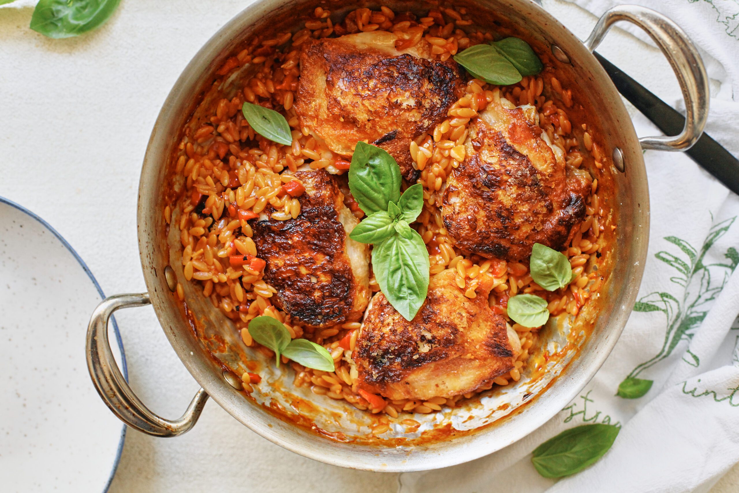 crispy chicken thighs with roasted red pepper orzo in a large pan