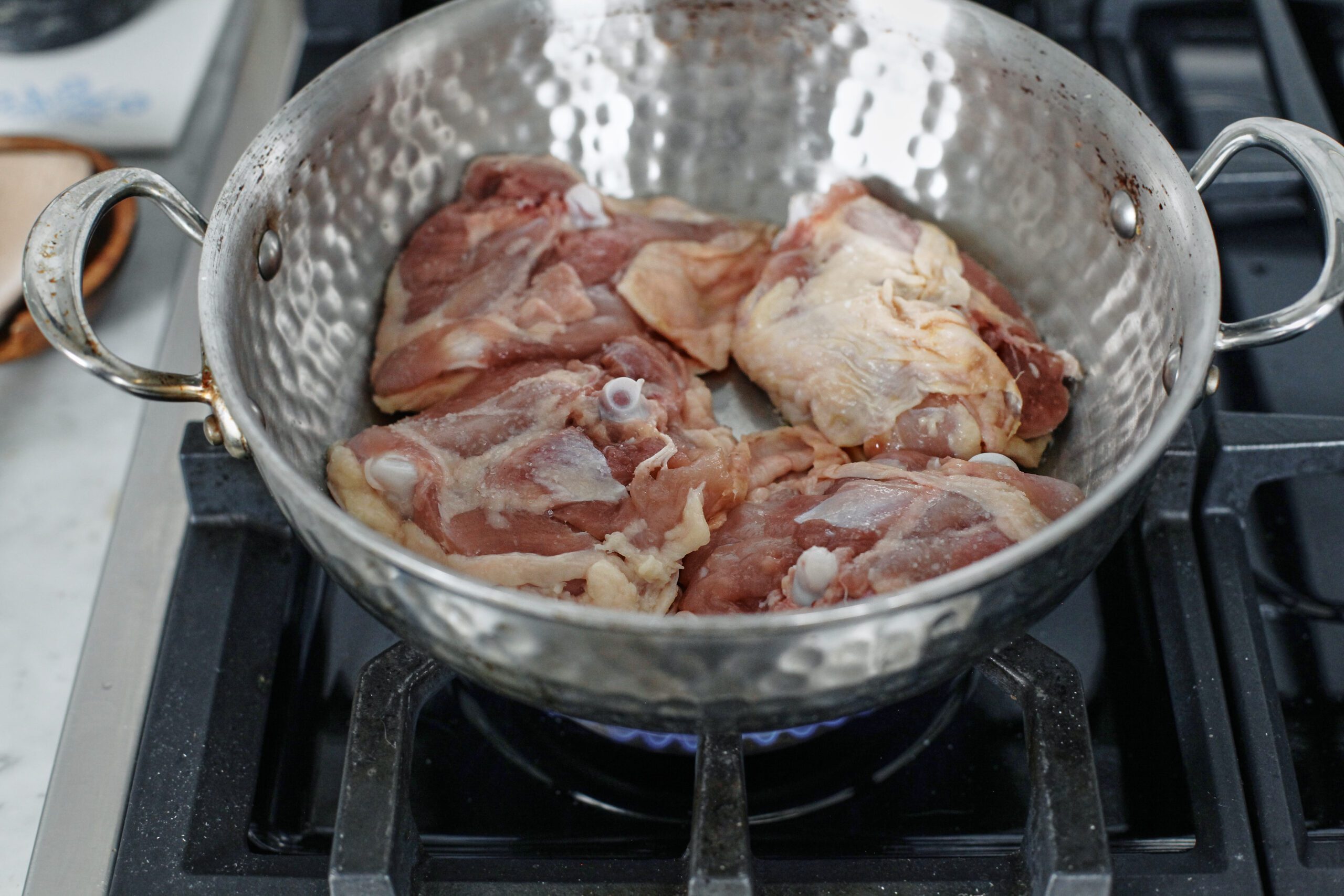 4 bone-in chicken thighs searing skin-side down in a large pan