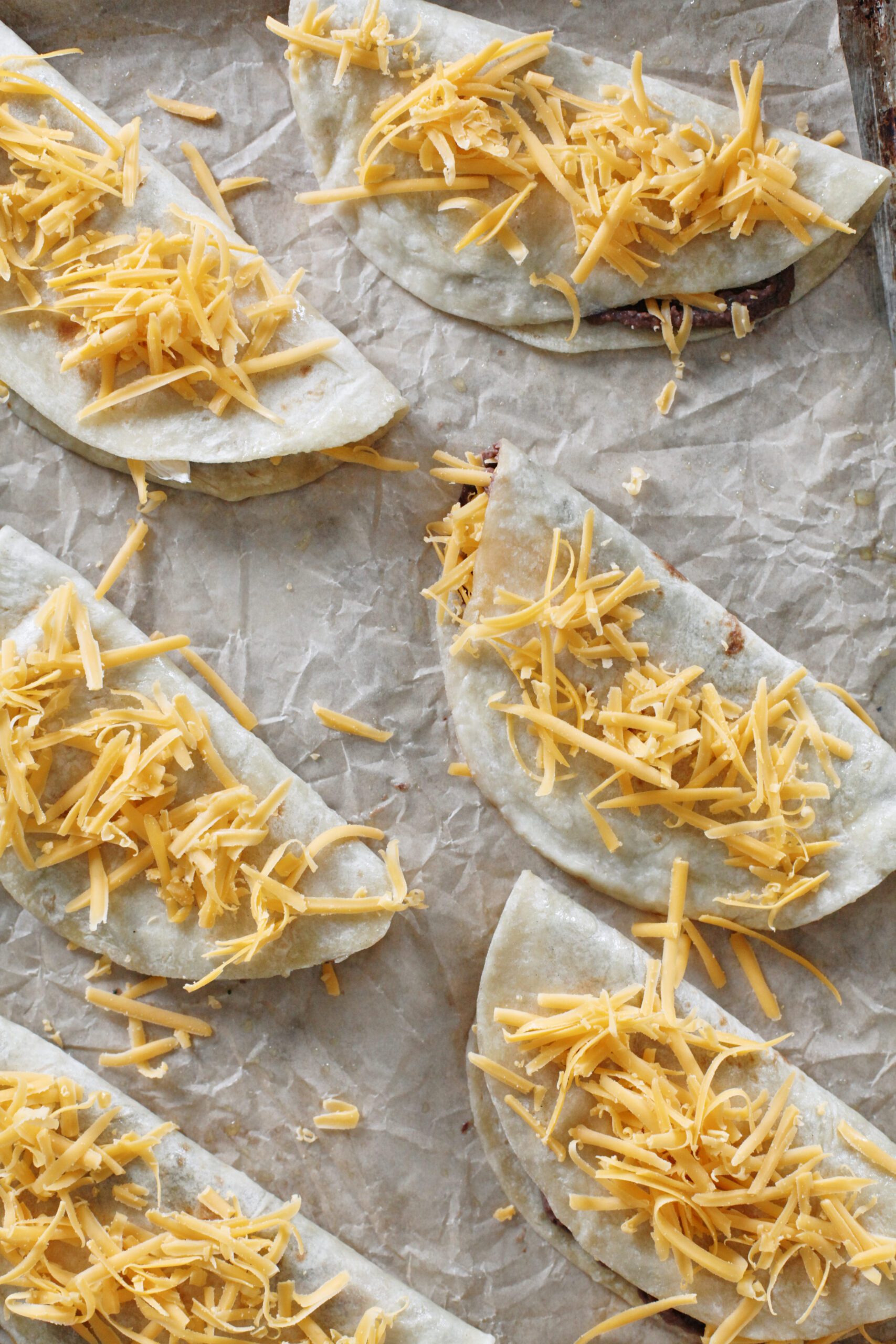 6 tortillas folded in half with cheese sprinkled over the top