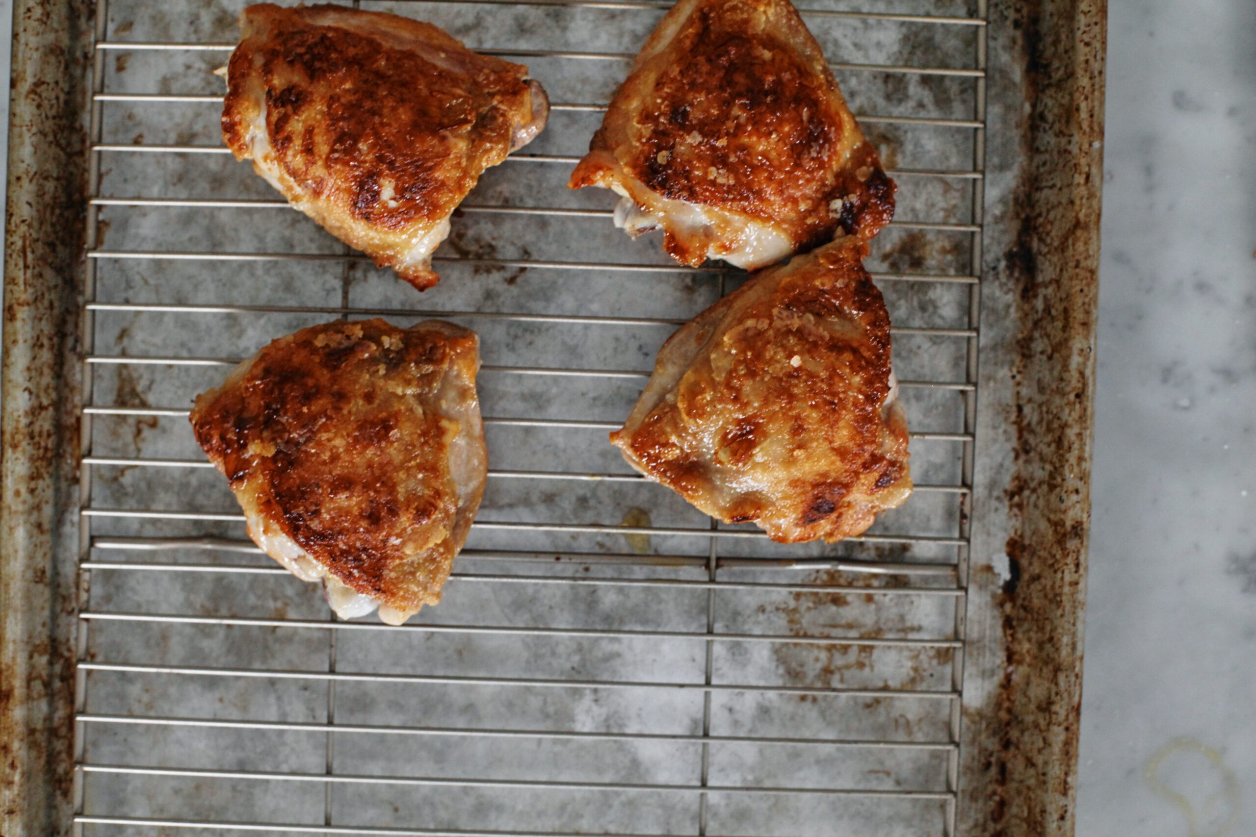 seared chicken thighs after cooking, on a wire rack