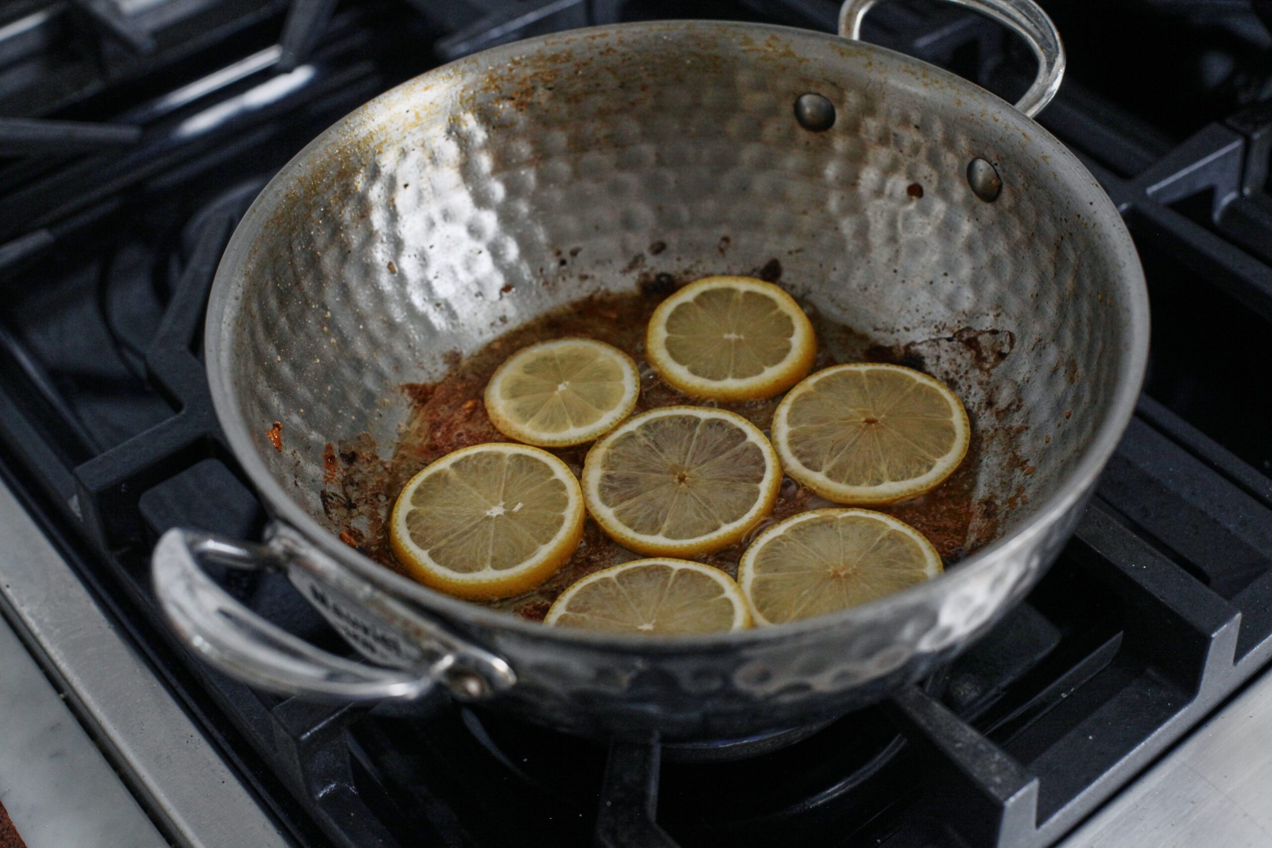 lemon slices searing in a pan in the rendered chicken fat