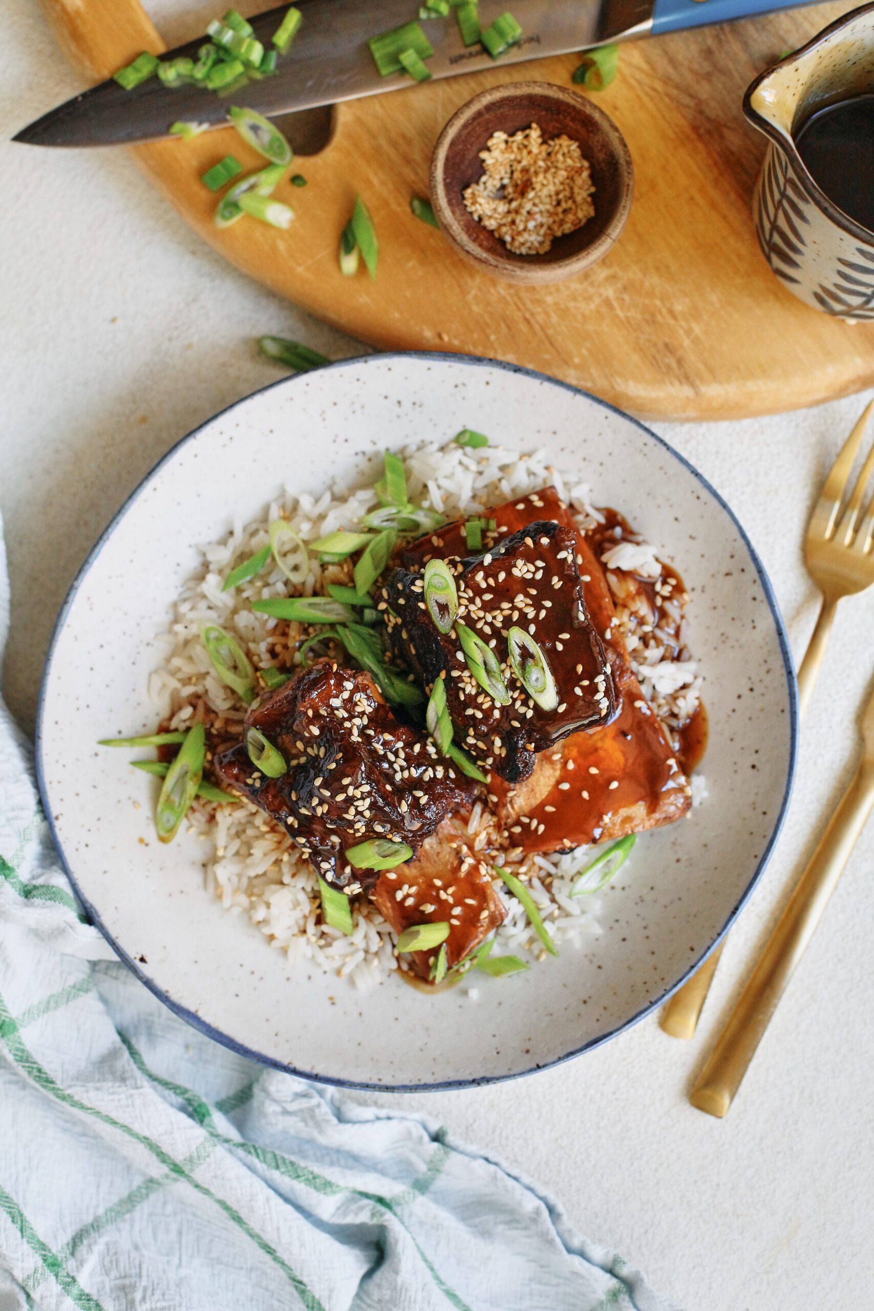 sticky soy and citrus short ribs over white rice, garnished with green onions and sesame seeds