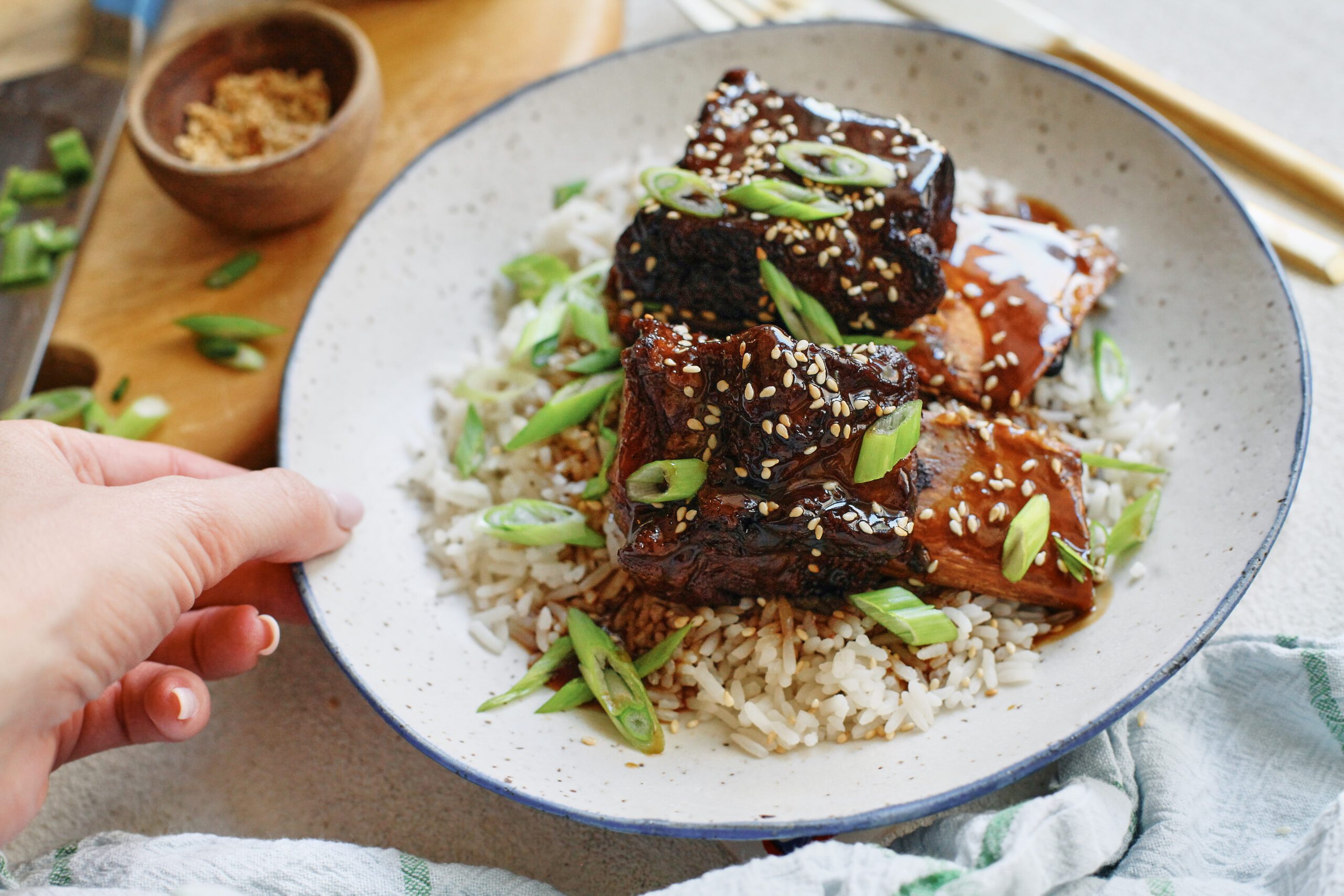 sticky soy and citrus short ribs over white rice, garnished with green onions and sesame seeds