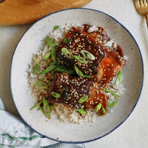 sticky soy and citrus short ribs over white rice, garnished with green onions and sesame seeds