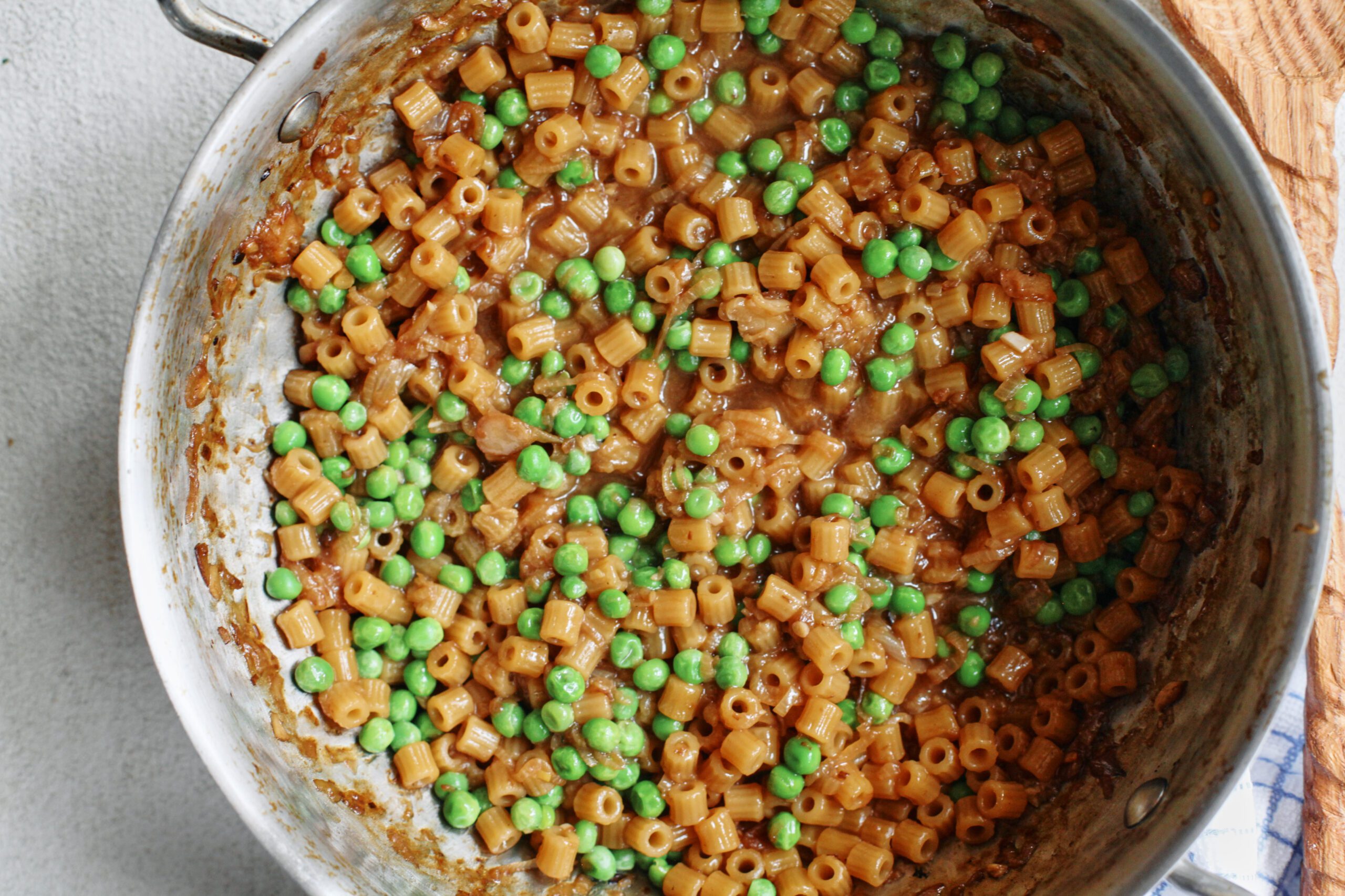 overhead photo of caramelized shallot ditalini with peas in a sauté pan